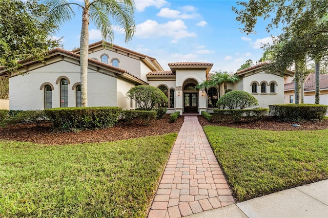 mediterranean / spanish-style house with french doors and a front lawn