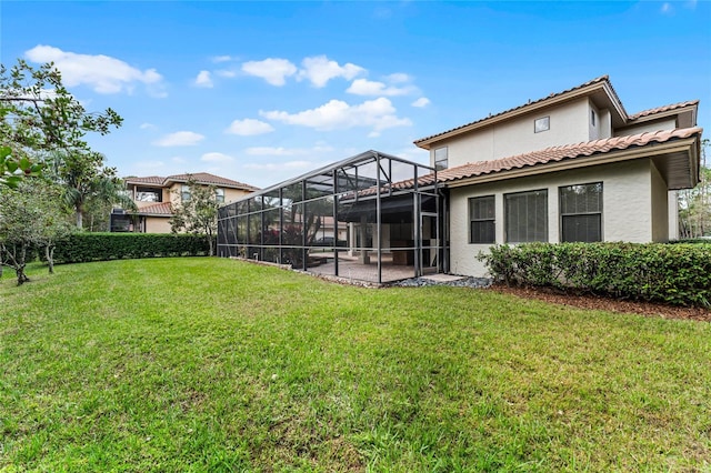 back of property featuring a yard and glass enclosure