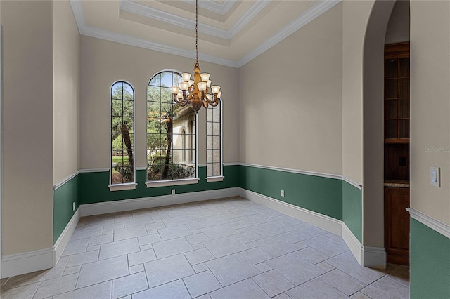 empty room with crown molding, a tray ceiling, and an inviting chandelier