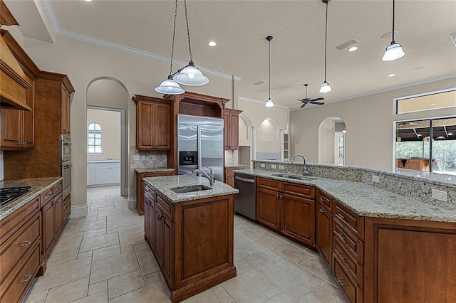 kitchen with appliances with stainless steel finishes, a kitchen island with sink, a healthy amount of sunlight, and sink