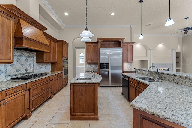 kitchen with sink, crown molding, an island with sink, decorative light fixtures, and stainless steel appliances