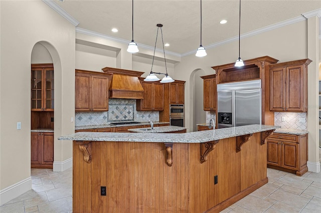 kitchen with stainless steel appliances, tasteful backsplash, a large island with sink, pendant lighting, and a kitchen bar