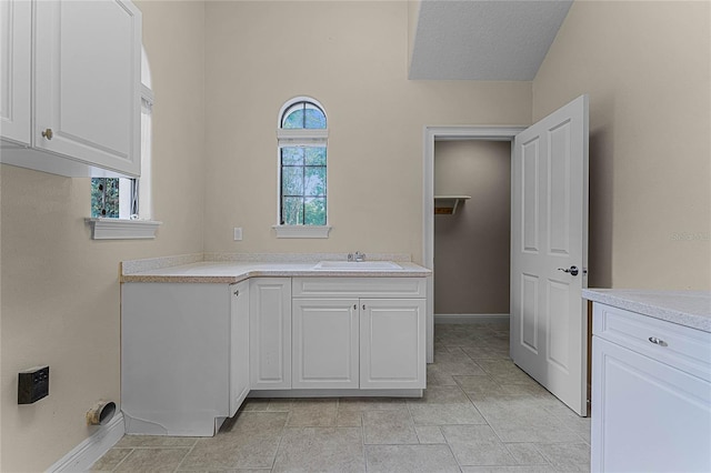 clothes washing area featuring a textured ceiling, sink, and a wealth of natural light