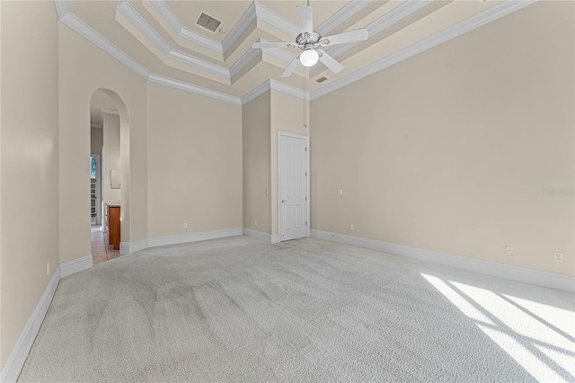 carpeted spare room featuring a tray ceiling, crown molding, ceiling fan, and a high ceiling