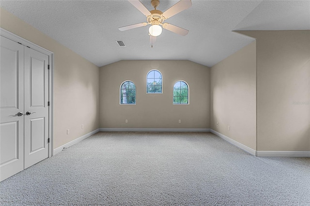 carpeted empty room with a textured ceiling, ceiling fan, and vaulted ceiling