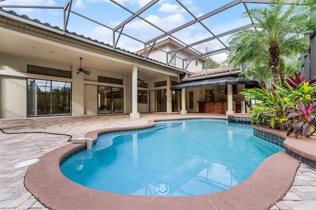 view of swimming pool featuring glass enclosure, ceiling fan, a bar, and a patio