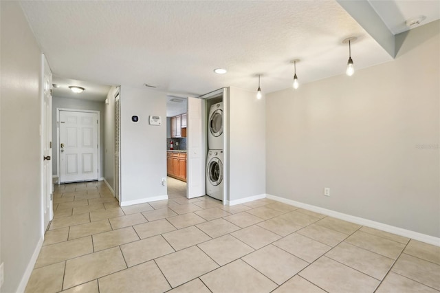 laundry room with stacked washer and dryer, light tile patterned flooring, and a textured ceiling