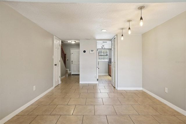 tiled empty room with a textured ceiling