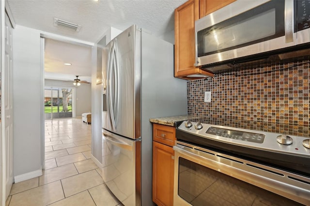 kitchen with backsplash, ceiling fan, a textured ceiling, light tile patterned flooring, and stainless steel appliances