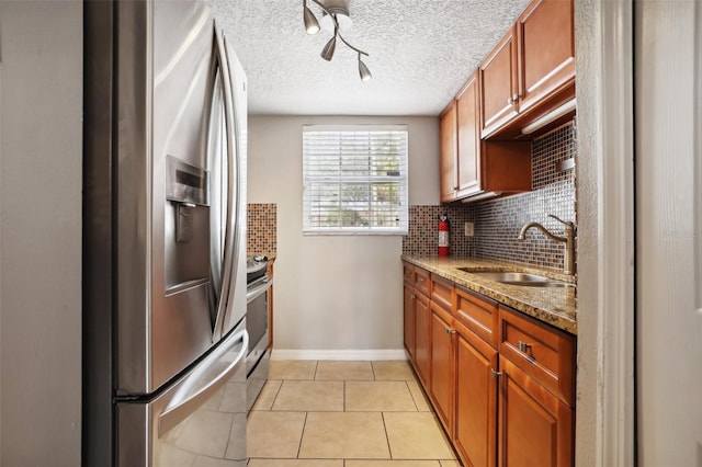 kitchen featuring backsplash, sink, light stone countertops, light tile patterned floors, and stainless steel appliances