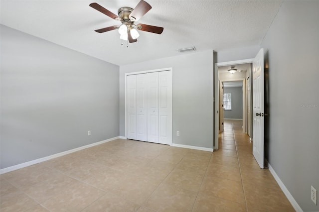 unfurnished bedroom with light tile patterned floors, a textured ceiling, a closet, and ceiling fan