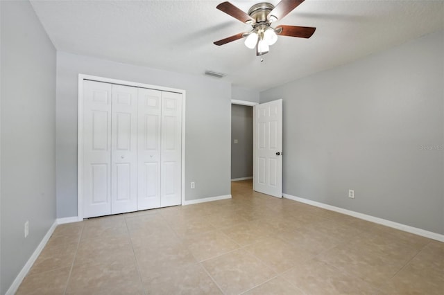 unfurnished bedroom with ceiling fan, light tile patterned floors, a textured ceiling, and a closet