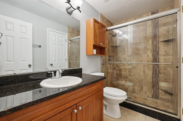 bathroom with tile patterned floors, a textured ceiling, toilet, a shower with door, and vanity