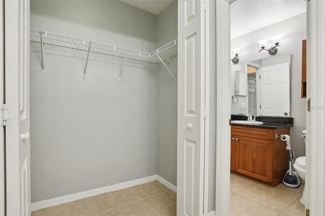 walk in closet featuring sink and light tile patterned floors