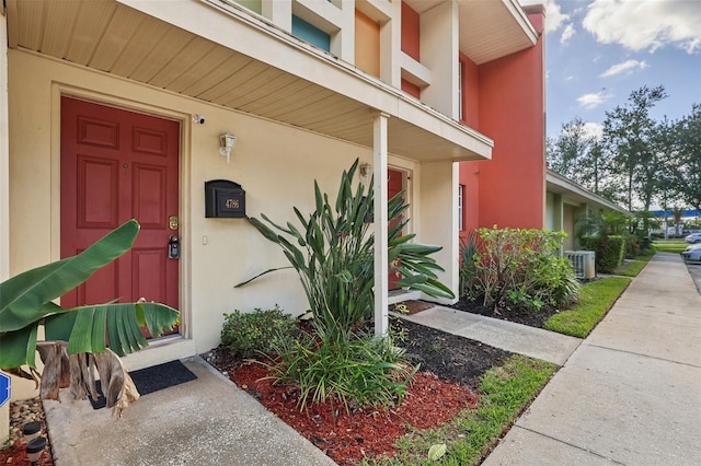 doorway to property with a porch and central AC unit