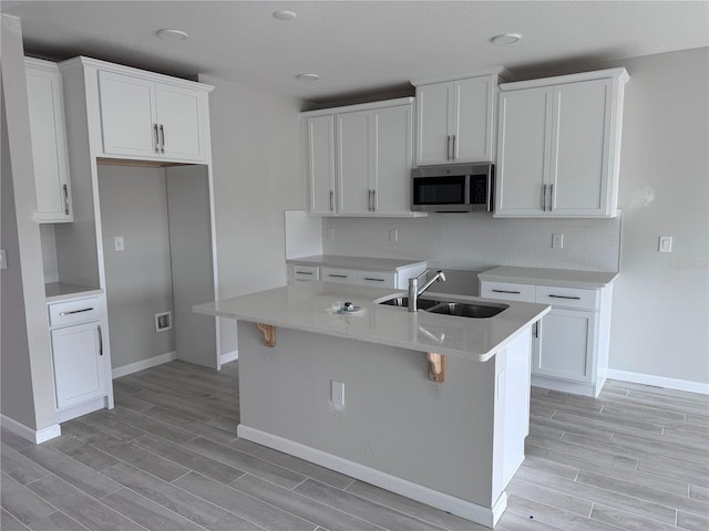 kitchen featuring a center island with sink, white cabinets, and sink