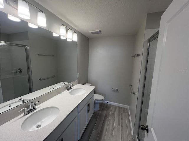 full bath featuring toilet, wood tiled floor, visible vents, and a sink