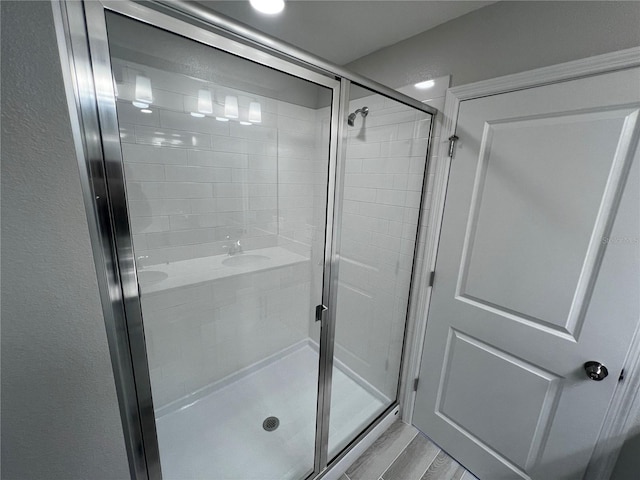 full bathroom featuring a stall shower and wood finished floors