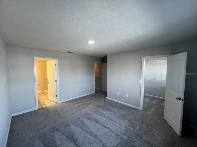 unfurnished bedroom featuring carpet floors, visible vents, a spacious closet, and baseboards