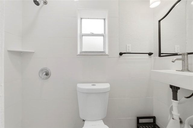 bathroom featuring sink, tile walls, and toilet