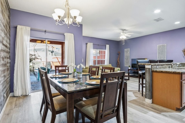 dining room featuring ceiling fan with notable chandelier and light hardwood / wood-style flooring