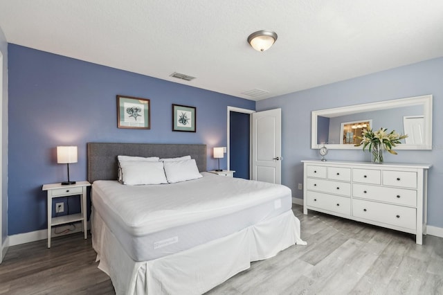 bedroom with a textured ceiling and light hardwood / wood-style flooring