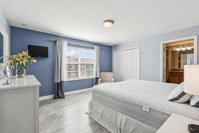 bedroom with a closet, ensuite bathroom, light hardwood / wood-style flooring, and a textured ceiling