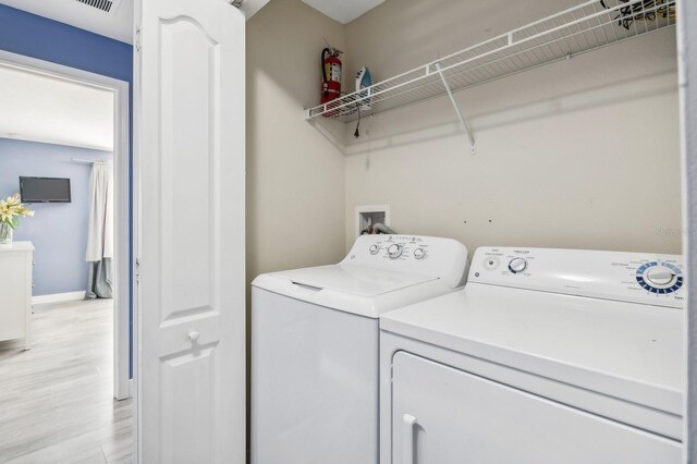 clothes washing area featuring independent washer and dryer and light wood-type flooring