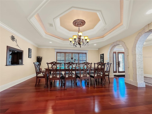 dining area with a chandelier, ornamental molding, a raised ceiling, and dark wood-type flooring