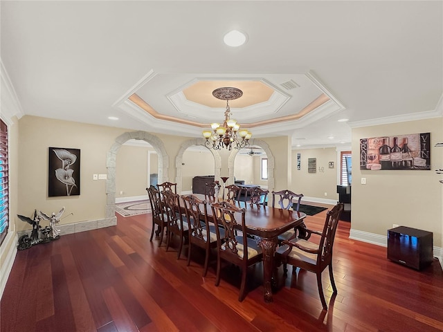 dining room with a tray ceiling, dark hardwood / wood-style flooring, a chandelier, and ornamental molding