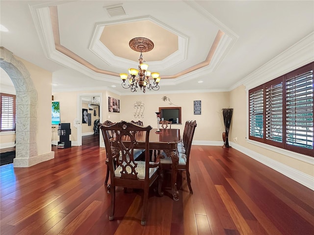 dining room featuring a chandelier, a raised ceiling, dark wood-type flooring, and crown molding