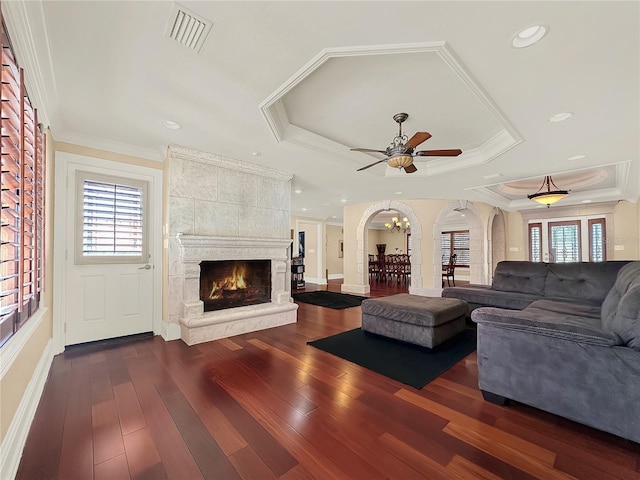 living room featuring a raised ceiling, a fireplace, dark hardwood / wood-style flooring, and ornamental molding