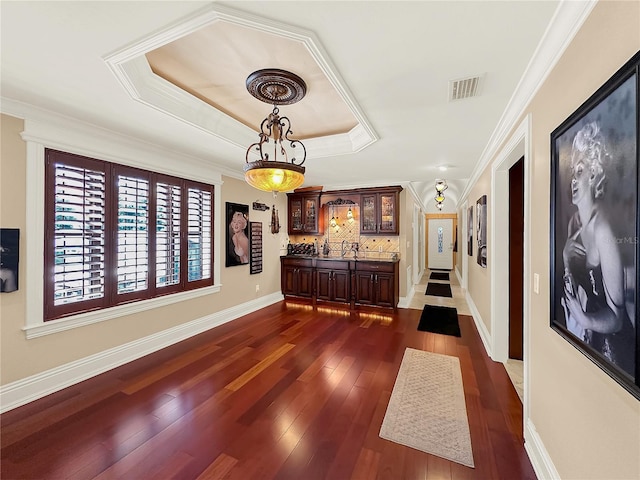 hallway with dark hardwood / wood-style floors, crown molding, a tray ceiling, and sink