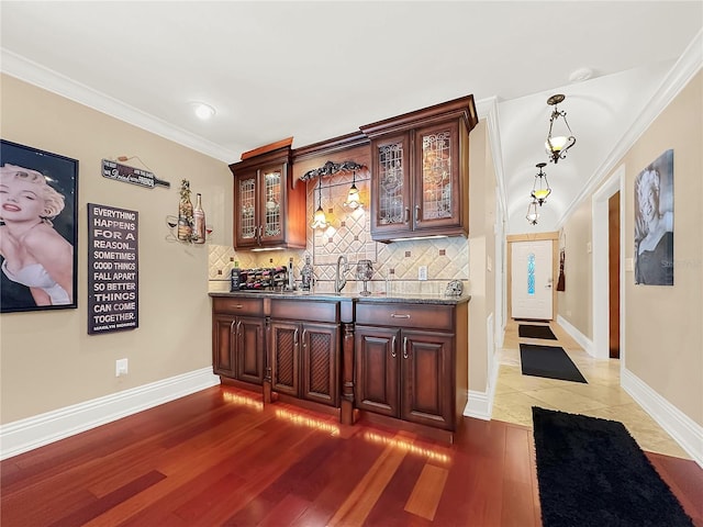 bar featuring tasteful backsplash, pendant lighting, dark wood-type flooring, and ornamental molding