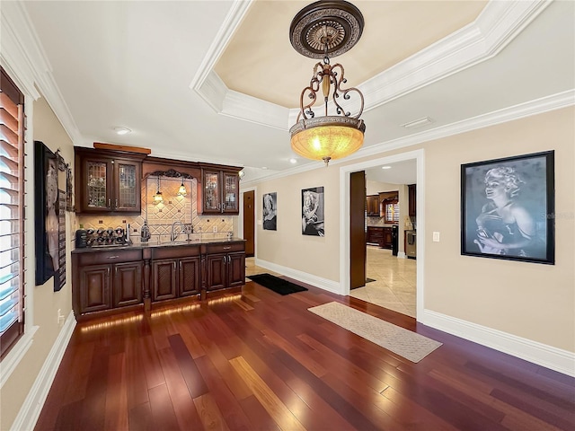 interior space featuring dark hardwood / wood-style flooring, ornamental molding, dark brown cabinetry, a raised ceiling, and sink