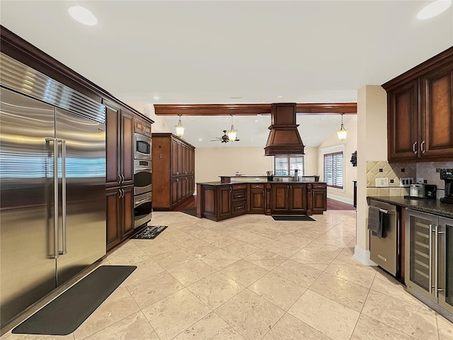 kitchen with hanging light fixtures, tasteful backsplash, a notable chandelier, built in appliances, and dark brown cabinets