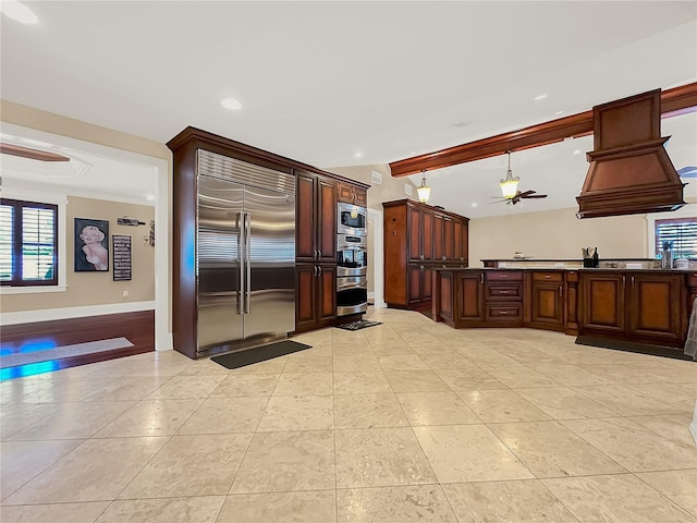 kitchen featuring built in appliances, ceiling fan, crown molding, and a wealth of natural light