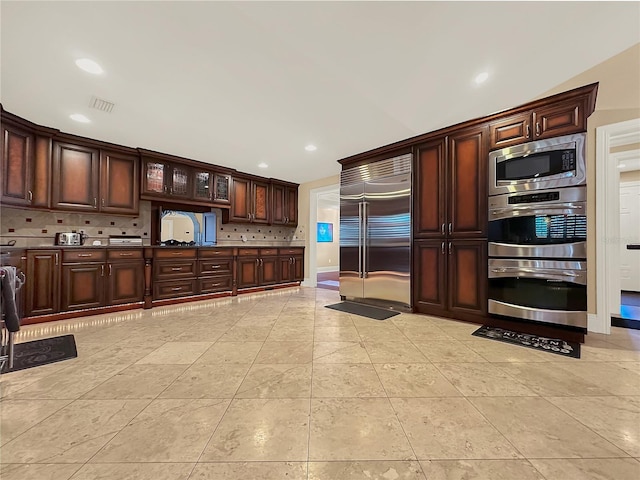 kitchen featuring built in appliances, dark brown cabinets, lofted ceiling, and backsplash