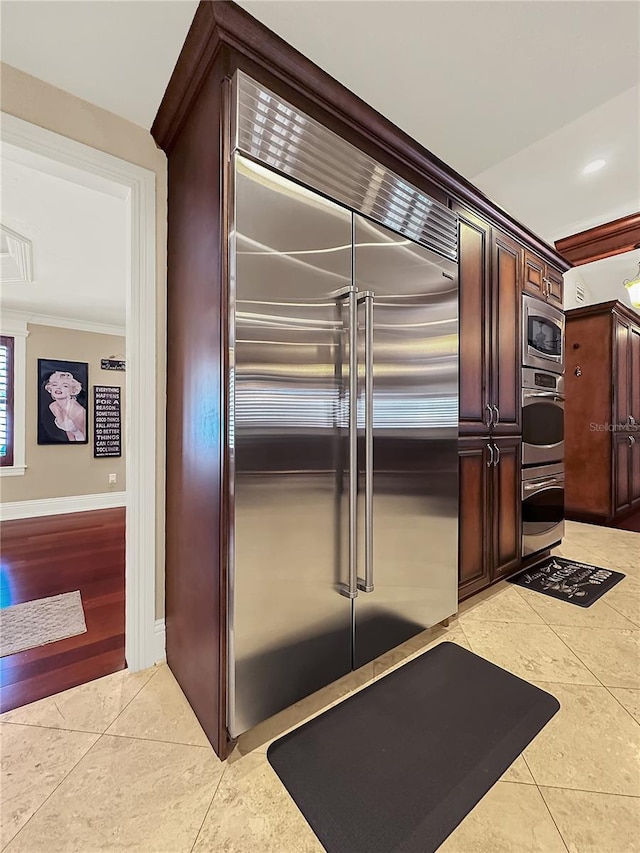 kitchen with light wood-type flooring, built in appliances, and crown molding