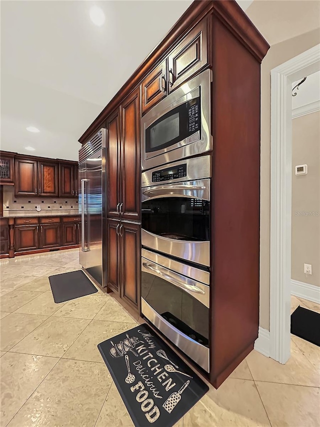 kitchen featuring backsplash, built in appliances, and light tile patterned floors