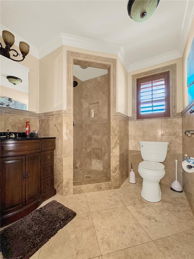 bathroom with vanity, toilet, ornamental molding, and tiled shower