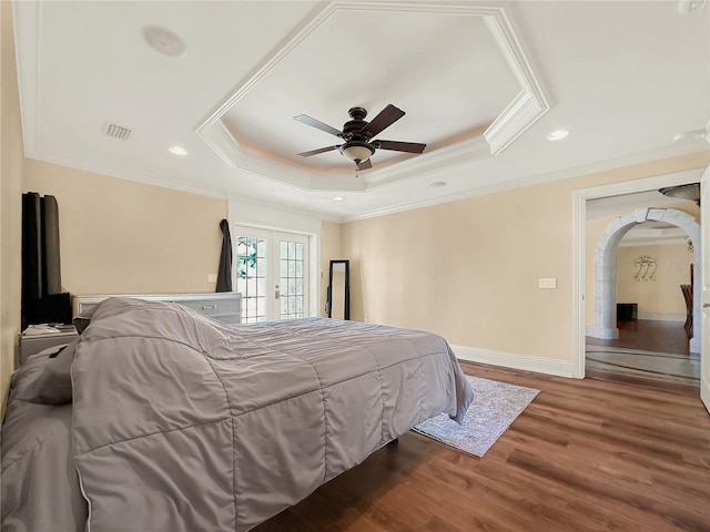 bedroom featuring ceiling fan, french doors, a raised ceiling, crown molding, and wood-type flooring