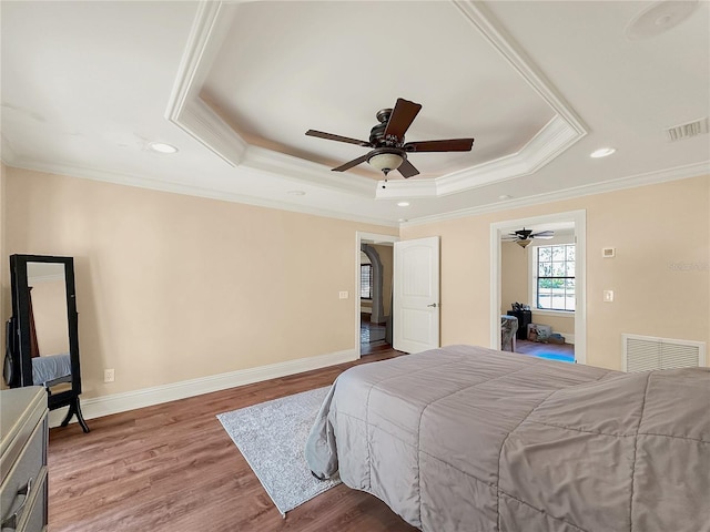 bedroom with a tray ceiling, ceiling fan, crown molding, and hardwood / wood-style flooring