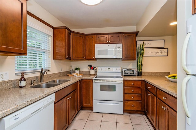 kitchen featuring light stone countertops, light tile patterned floors, white appliances, and sink