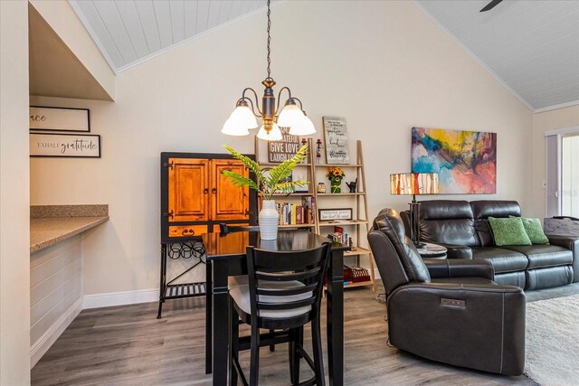 dining space with crown molding, lofted ceiling, dark wood-type flooring, and an inviting chandelier