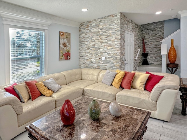 living room featuring a textured ceiling, light wood-type flooring, and crown molding