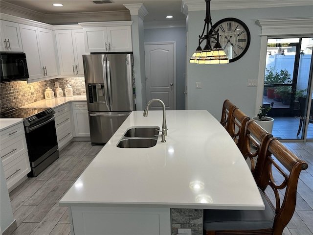 kitchen with light wood-type flooring, sink, black appliances, a center island with sink, and white cabinetry