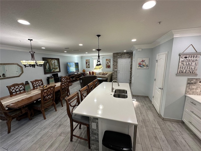 kitchen featuring white cabinetry, sink, light hardwood / wood-style floors, and ornamental molding