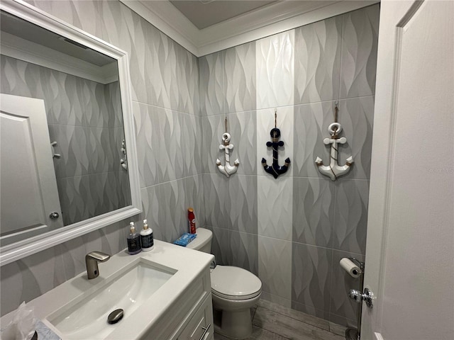 bathroom with vanity, toilet, tile walls, and ornamental molding