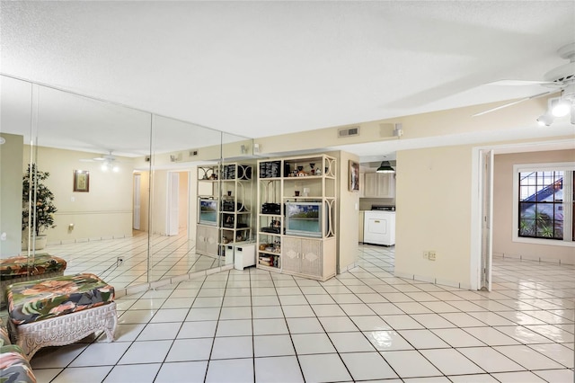 interior space with washer / clothes dryer, ceiling fan, and light tile patterned floors